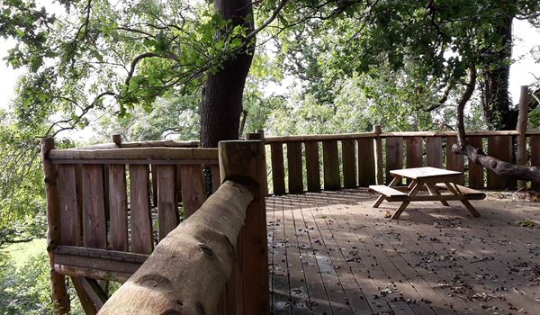 an empty park bench sitting on top of a wooden fence